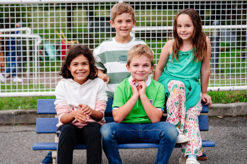 Quatre élèves de primaire assis sur un banc