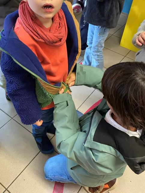 Uneélève aide son camarade à fermer son manteau